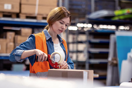 Ung kvinnlig arbetare i lagermiljö.